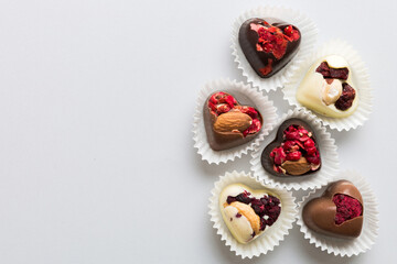 chocolate sweets in the form of a heart with fruits and nuts on a colored background. top view with space for text, holiday concept