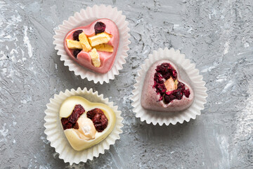 chocolate sweets in the form of a heart with fruits and nuts on a colored background. top view with space for text, holiday concept