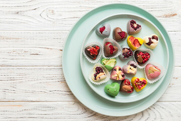 Plate with different chocolate on colored background. Assortment of fine chocolates top view vith copy space Health and obesity concept