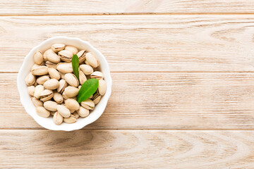Fresh healthy Pistachios in bowl on colored table background. Top view Healthy eating concept. Super foods