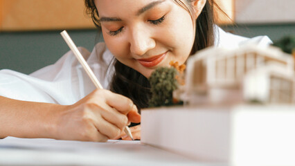 Closeup of young beautiful architect engineer drawing blueprint while looking at architectural...