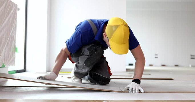 Wizard of floor coverings of flooring. Installation of laminate on floor and man working