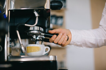 A barista prepares coffee using an espresso machine. Close-up of a man preparing coffee in a cafe.