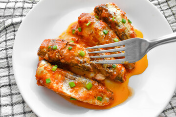 Canned fish sardines in tomato sauce on a white plate. 