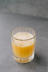 Close up of a glass of orange juice on a gray stone background.