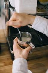 A barista prepares milk for cappuccino using an espresso machine. Close-up of a man preparing coffee in a cafe.