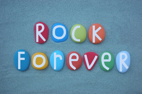 Rock forever, creative slogan composed with hand painted multi colored stone letters over green sand