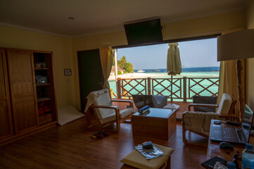 View from the interior of the apartment through the panoramic window to the terrace with a view of the sea lagoon and part of the coast.