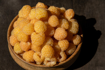 Yellow raspberries in a wooden bowl on the table. Summer berries background. Vitamin food, berry harvest. Healthy nutrition.