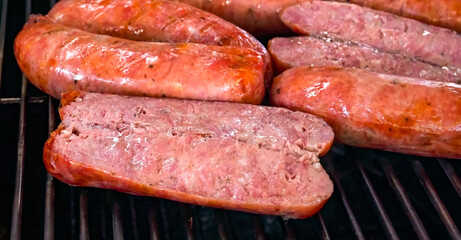 Hot Dog preparation, freshly grilled sausages, close up. Homemade hot dog sausage cooking. Grocery product advertising, menu or package, selective focus.
