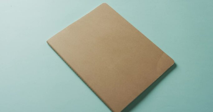 Close up of closed brown book with copy space on green background in slow motion