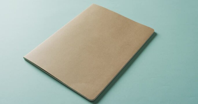 Close up of closed brown book with copy space on green background in slow motion