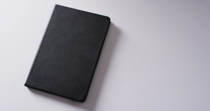 Close up of closed black book with copy space on white background in slow motion