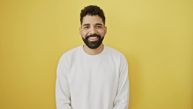 Cheerful young man exuding cool confidence, standing tall with a beaming smile on his face. lucky person isolated against vibrant yellow background radiating sheer happiness and success.