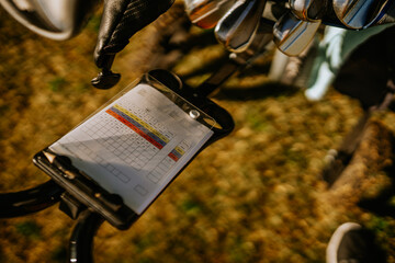 Sotogrante, Spain - January 25, 2024 - a golf scorecard on a clipboard, with a set of golf clubs in...