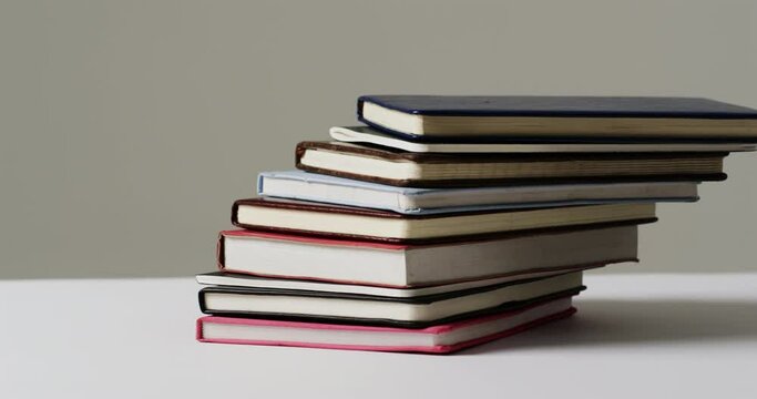 Close up of stack of books on grey background, in slow motion