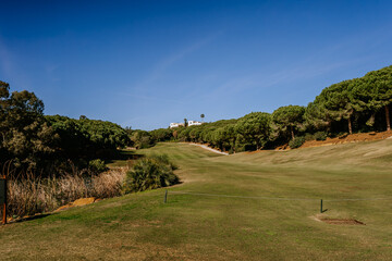 Fototapeta na wymiar Sotogrante, Spain - January 25, 2024 - A scenic view of a golf course with a clear sky, greenery, and a villa in the distance.