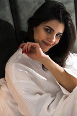 Fototapeta premium A nice woman wakes up in a hotel room and enjoys the view from the window in winter. Coffee in bed. Hotel holiday concept