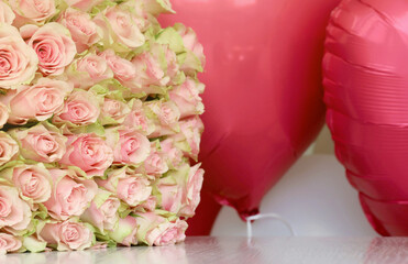 Bouquet of colorful roses and red balloons in shape of heart closeup. Pink flowers full frame