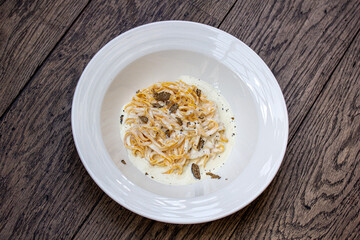 Spaghetti with mushroom on white plate on wooden table, top view