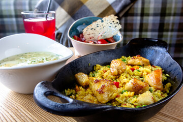 Pilaf with chicken and vegetables in a pan on a wooden table