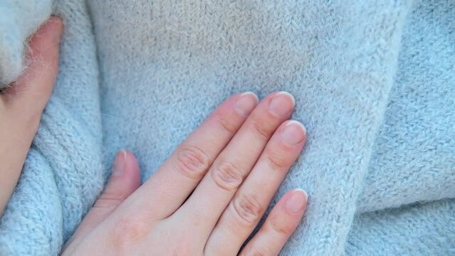 Close-up woman hand stroking over the surface knitted soft wool alpaca cloth or warm fluffy sweater. Handcraft blue knitting woolen fabric
