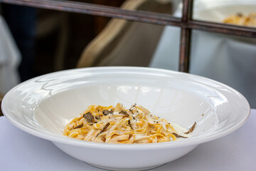 Spaghetti carbonara in white dish on table in restaurant, close up