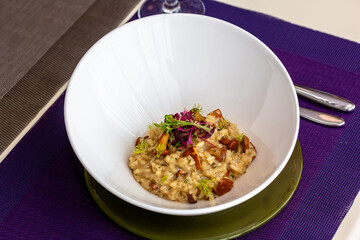 Risotto with mushrooms in a white bowl on a table