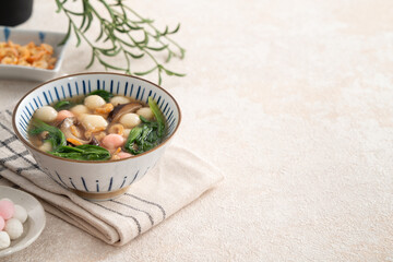 Eating red and white small tangyuan with savory soup and vegetable.