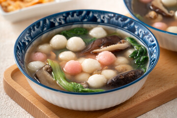 Eating red and white small tangyuan with savory soup and vegetable.