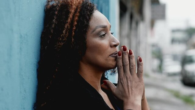 One struggling black woman feeling overwhelmed and anxiety during difficult times pleading help for a higher power in urban sidewalk setting, desperate person seeking HELP