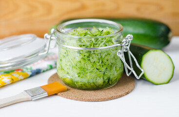 Fresh grated zucchini in a glass jar. Ingrediet for preparing homemade face or hair mask, natural beauty treatment and spa recipe.