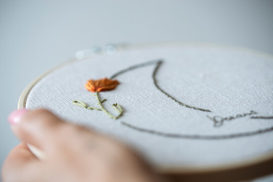 Woman's hand holding an embroidery hoop with a floral moon design