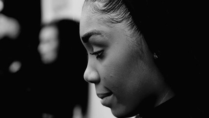 Preoccupied African American young woman with thoughtful gaze  and deep soulful reflection captured in black and white. Close-up face of a black latina adult girl feeling angst