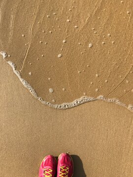 Personal perspective view of a woman in trainers standing on beach at water's edge, Hong Kong, China