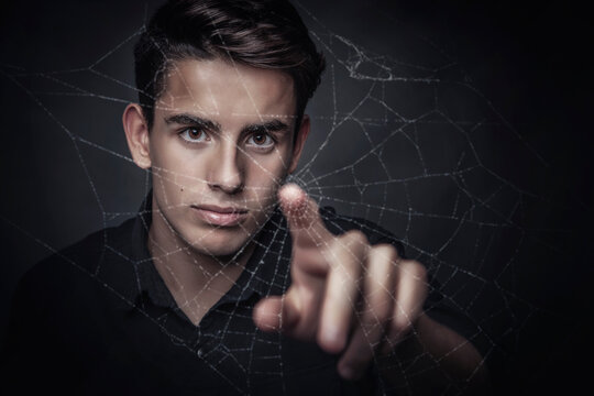 Teenage boy touching the middle of a spider's web with his index finger