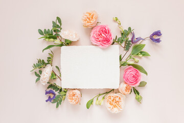 Overhead view of roses, chrysanthemums and alstroemeria flowers arranged around a blank white card