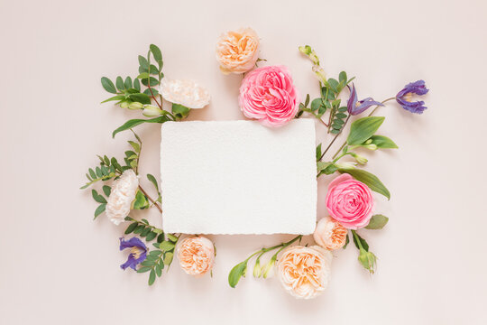 Overhead view of roses, chrysanthemums and alstroemeria flowers arranged around a blank white card
