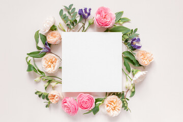 Overhead view of roses, chrysanthemums and alstroemeria flowers arranged around a blank white card