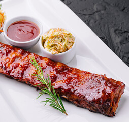 Grilled pork ribs in barbecue sauce and honey with sauerkraut on white plate