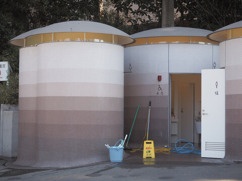 TOKYO, JAPAN - January 30, 2024: A Toyo Ito-designed public toilet, which is being cleaned, in Tokyo's Shinjuku area near Yoyogi-Hachiman shrine. It's part of the Tokyo Toilet Project.