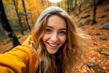 Fototapeta premium Happy young woman taking selfie in the autumn forest