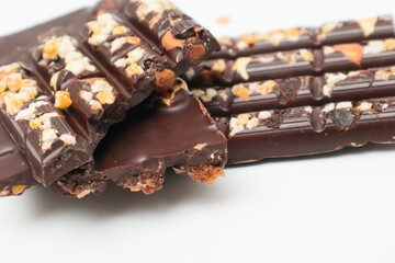 Dark chocolate bars with chopped nuts on a white background, side view. Dessert food. Dark chocolate in Pieces.