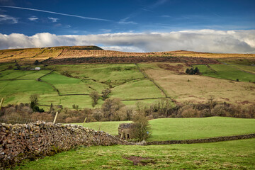With a well kept field barn, a view looking west across White Scar towards Wasset Fell from the single track road from West Burton to Walden