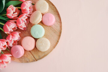 Bouquet of pink tulips and macaroons on pink background. Anniversary celebration concept. Copy space. Top view