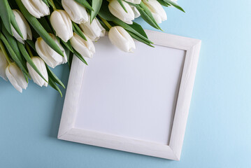 Wooden border decorated bouquet of white tulips on blue background. Anniversary celebration concept. Soft focus