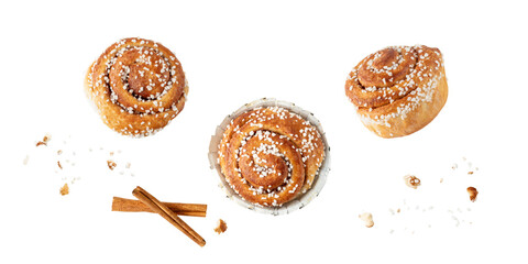 Fresh baked cinnamon buns kanelbulle with crumbs flying falling isolated on white background.