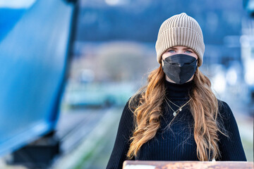 Woman with long red hair and a hat wears an FFP 2 protective mask.