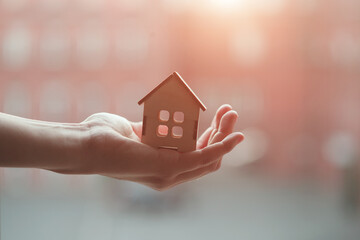 Real estate agent's hand holding wooden house model from natural material, buy sell, rent and best...