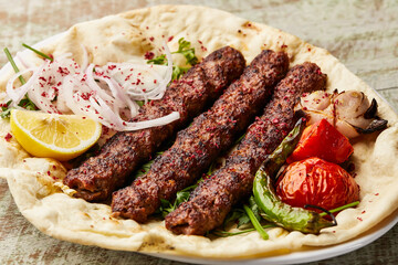 Arabic Meat Kabab with saffron, onion, tomato, pita bread, lemon slice and salad served in dish...